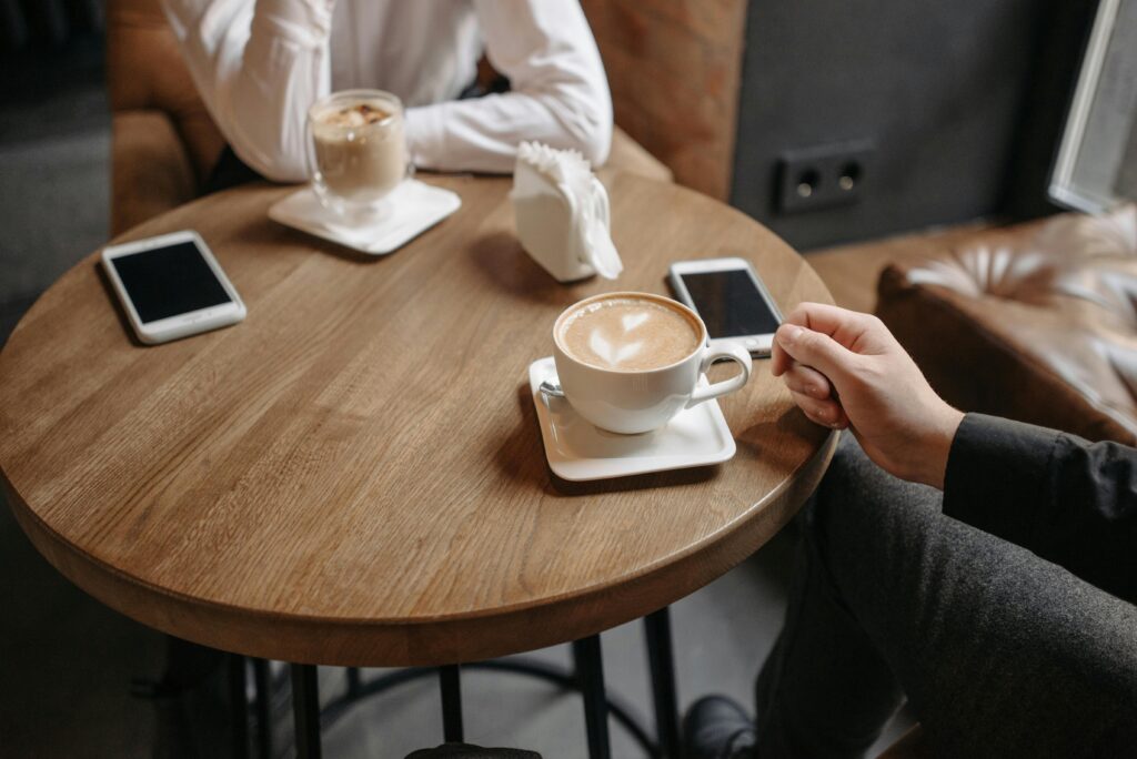 two cups of coffee on a table with two people across from each other