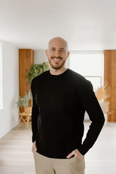 diskin young wearing a black sweater and khaki pants smiling