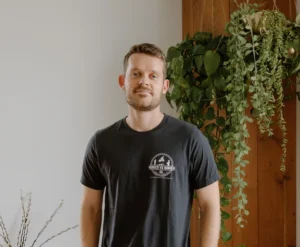 ethan hunger wearing a black tshirt, khaki pants, standing with his hands in his pockets
